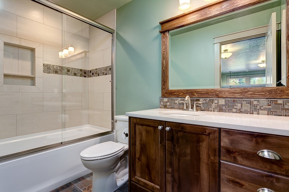 Bathroom - large craftsman 3/4 brown tile, gray tile and glass tile ceramic tile bathroom idea in Boise with recessed-panel cabinets, dark wood cabinets, a two-piece toilet, green walls, an undermount sink and quartz countertops