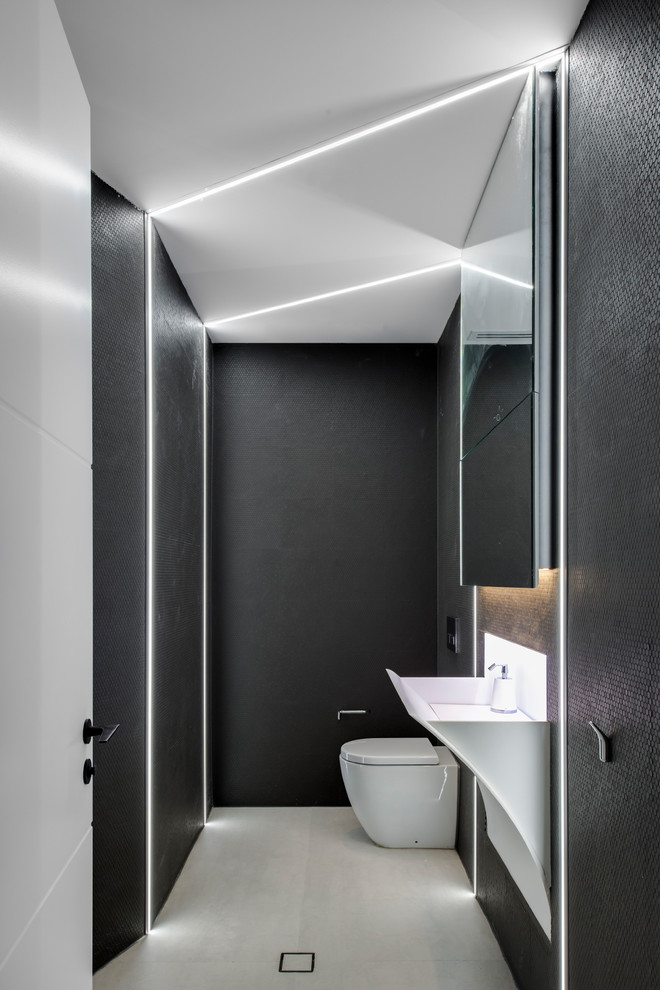 Aménagement d'une petite salle de bain contemporaine avec un placard avec porte à panneau encastré, des portes de placard noires, un carrelage noir, mosaïque, un plan de toilette en surface solide et un plan de toilette blanc.