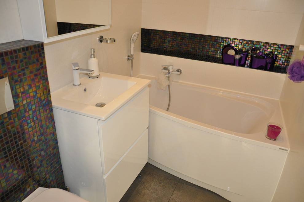 Photo of a small contemporary ensuite bathroom in Other with an integrated sink, shaker cabinets, white cabinets, a corner bath, a wall mounted toilet, white tiles, glass tiles, white walls and porcelain flooring.