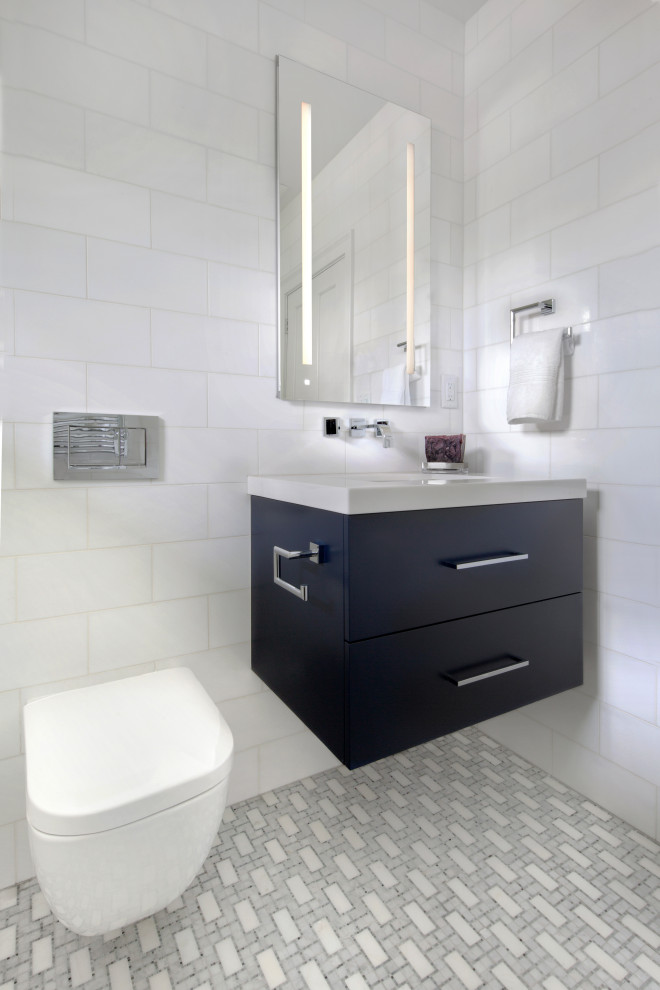 Idéer för mellanstora funkis vitt badrum, med släta luckor, blå skåp, en vägghängd toalettstol, vit kakel, marmorkakel, vita väggar, mosaikgolv, ett undermonterad handfat, marmorbänkskiva och grått golv