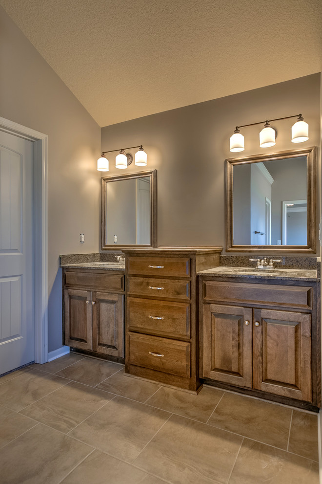 Medium sized traditional ensuite bathroom in Kansas City with raised-panel cabinets, medium wood cabinets, granite worktops, a built-in bath, grey tiles, ceramic tiles, grey walls, ceramic flooring, an alcove shower, a submerged sink and an open shower.