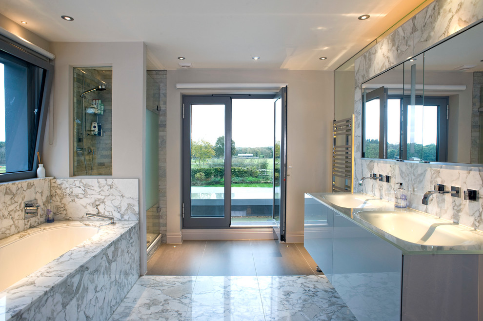 ロンドンにあるコンテンポラリースタイルのおしゃれなマスターバスルーム (フラットパネル扉のキャビネット、グレーのキャビネット、アルコーブ型シャワー、グレーのタイル、白い壁、一体型シンク、ガラスの洗面台、グレーの床、開き戸のシャワー) の写真