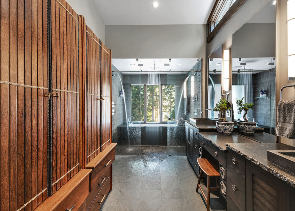Example of a large mountain style master gray tile gray floor wet room design in Sacramento with louvered cabinets, dark wood cabinets, an undermount tub, gray walls, a drop-in sink and brown countertops
