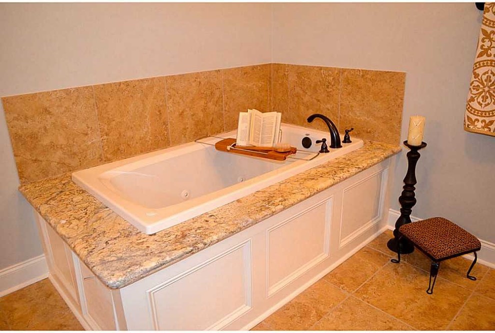 Réalisation d'une salle de bain principale tradition en bois brun de taille moyenne avec un lavabo encastré, un placard avec porte à panneau surélevé, un plan de toilette en granite, une baignoire posée, un carrelage beige, des carreaux de porcelaine, un mur gris et un sol en carrelage de porcelaine.