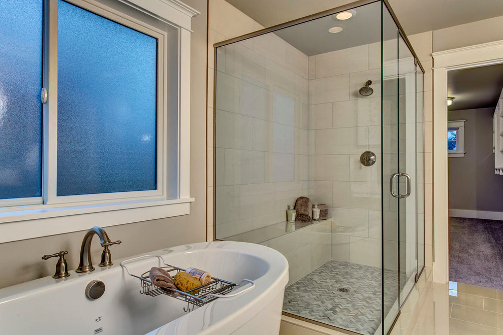 Bild på ett en-suite badrum, med släta luckor, vita skåp, ett fristående badkar, en öppen dusch, en toalettstol med hel cisternkåpa, beige kakel, stickkakel, grå väggar, klinkergolv i keramik, ett undermonterad handfat och marmorbänkskiva