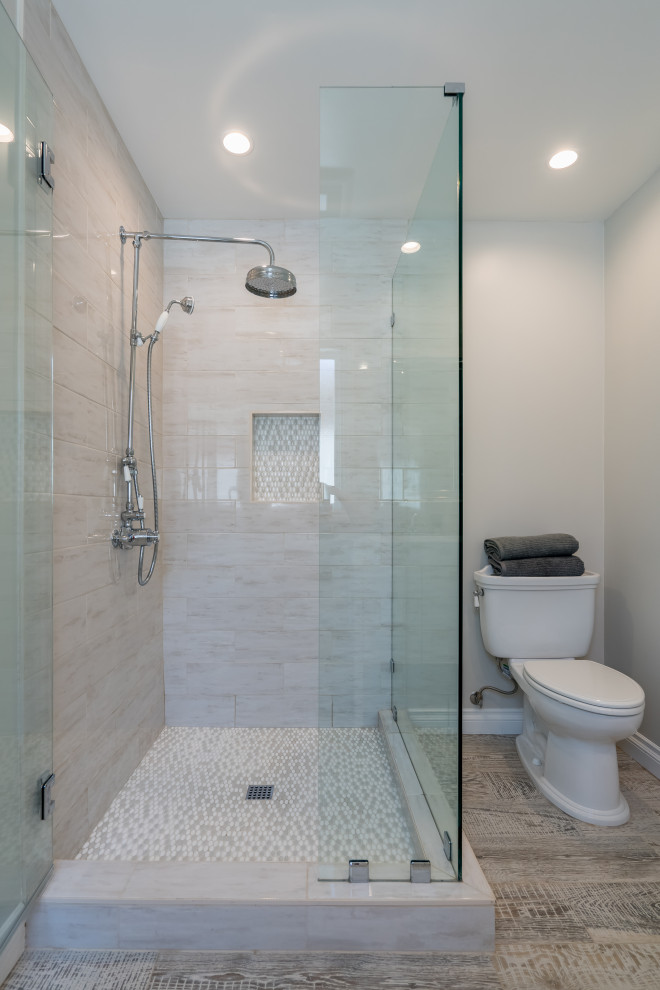Lantlig inredning av ett vit vitt en-suite badrum, med vita skåp, en hörndusch, grå kakel, grå väggar, ett fristående handfat, bänkskiva i akrylsten och dusch med gångjärnsdörr