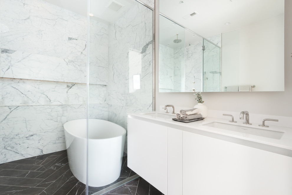 Foto på ett mellanstort skandinaviskt vit en-suite badrum, med släta luckor, vita skåp, ett fristående badkar, en kantlös dusch, vit kakel, marmorkakel, vita väggar, klinkergolv i keramik, ett nedsänkt handfat, svart golv och dusch med skjutdörr