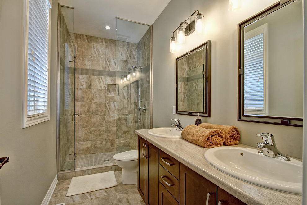 Exempel på ett klassiskt badrum med dusch, med skåp i shakerstil, skåp i mörkt trä, en dusch i en alkov, en toalettstol med separat cisternkåpa, beige kakel, grå kakel, porslinskakel, grå väggar, klinkergolv i porslin, ett nedsänkt handfat och bänkskiva i täljsten