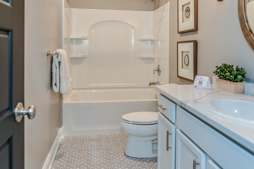 Свежая идея для дизайна: ванная комната среднего размера в стиле неоклассика (современная классика) с фасадами в стиле шейкер, серыми фасадами, ванной в нише, душем над ванной, унитазом-моноблоком, серыми стенами, полом из керамической плитки, накладной раковиной, столешницей из гранита, разноцветным полом, шторкой для ванной и белой столешницей - отличное фото интерьера