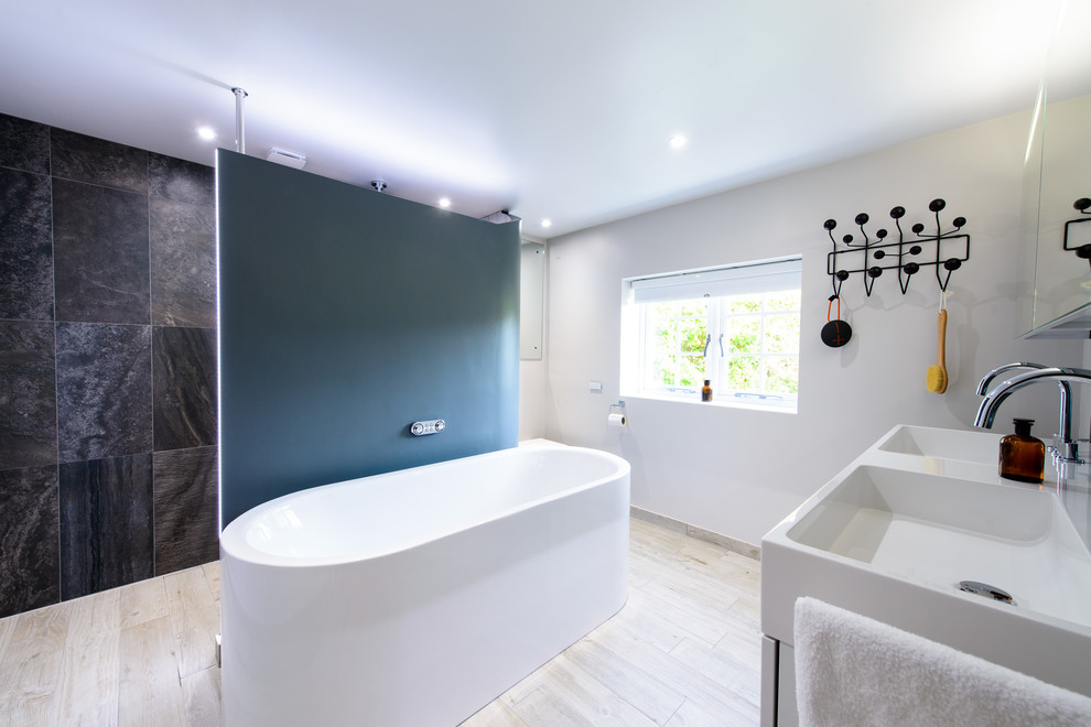 Foto på ett mellanstort funkis badrum, med ett fristående badkar, beige väggar, ljust trägolv och vitt golv