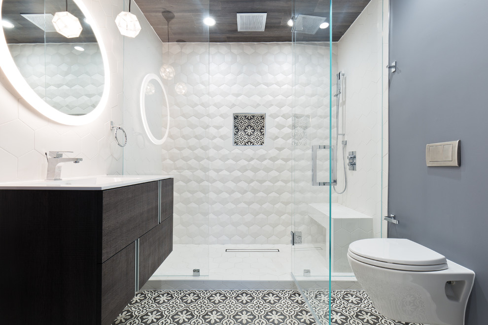 Bild på ett funkis vit vitt badrum med dusch, med släta luckor, skåp i mörkt trä, en dusch i en alkov, en vägghängd toalettstol, vit kakel, grå väggar, ett integrerad handfat, flerfärgat golv och dusch med gångjärnsdörr