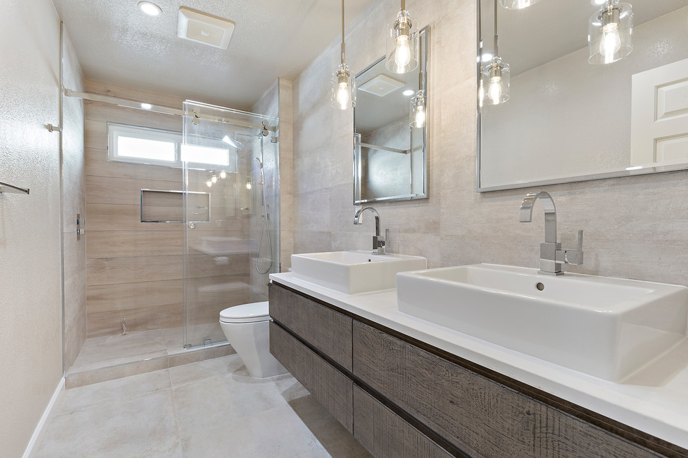 Inredning av ett modernt mellanstort vit vitt en-suite badrum, med släta luckor, skåp i mellenmörkt trä, en dusch i en alkov, en toalettstol med hel cisternkåpa, beige väggar, ett fristående handfat, bänkskiva i akrylsten, beiget golv och dusch med skjutdörr