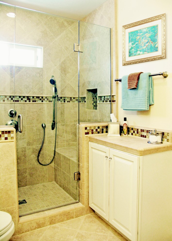 Exempel på ett litet klassiskt badrum med dusch, med luckor med upphöjd panel, vita skåp, kaklad bänkskiva, en dusch i en alkov, en toalettstol med separat cisternkåpa, beige kakel, porslinskakel, beige väggar och klinkergolv i porslin