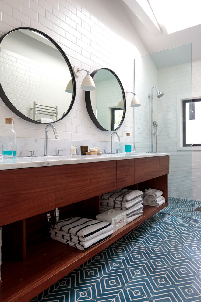Foto på ett funkis vit badrum, med släta luckor, skåp i mörkt trä, en kantlös dusch, vit kakel, tunnelbanekakel, vita väggar, klinkergolv i porslin, ett undermonterad handfat, marmorbänkskiva, blått golv och med dusch som är öppen