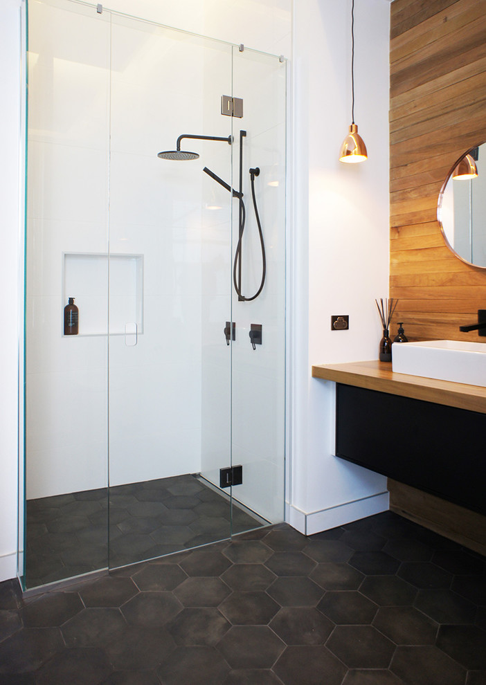 オークランドにある北欧スタイルのおしゃれなバスルーム (浴槽なし) (磁器タイル、アルコーブ型シャワー、白いタイル、ベッセル式洗面器、木製洗面台、黒い床、ブラウンの洗面カウンター) の写真