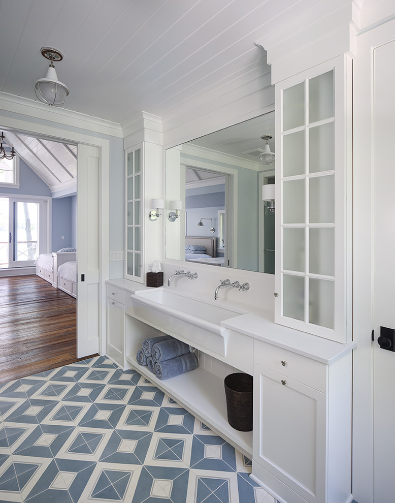 Cette image montre une salle de bain rustique avec un placard avec porte à panneau encastré, des portes de placard blanches, un mur bleu, une grande vasque et un sol bleu.