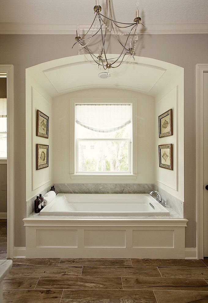 Klassisk inredning av ett mellanstort en-suite badrum, med skåp i shakerstil, vita skåp, ett badkar i en alkov, en toalettstol med separat cisternkåpa, grå väggar, mörkt trägolv, ett undermonterad handfat, marmorbänkskiva och brunt golv