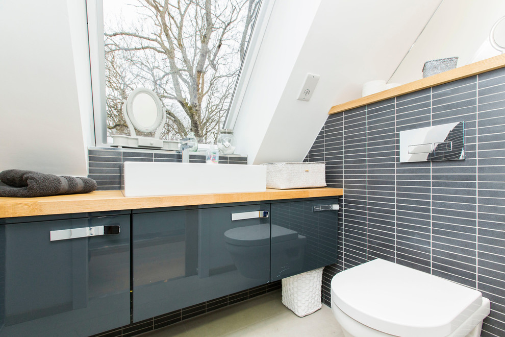 Design ideas for a small contemporary bathroom in Glasgow with flat-panel cabinets, grey cabinets, a one-piece toilet, grey tiles, a vessel sink, wooden worktops, beige worktops and matchstick tiles.