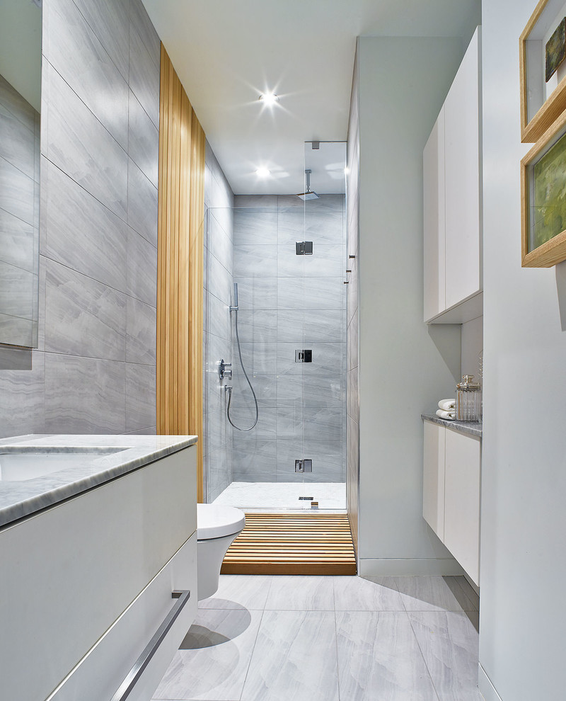 Foto di una stanza da bagno design con ante lisce, ante bianche, doccia alcova, piastrelle grigie, lavabo sottopiano e pavimento grigio