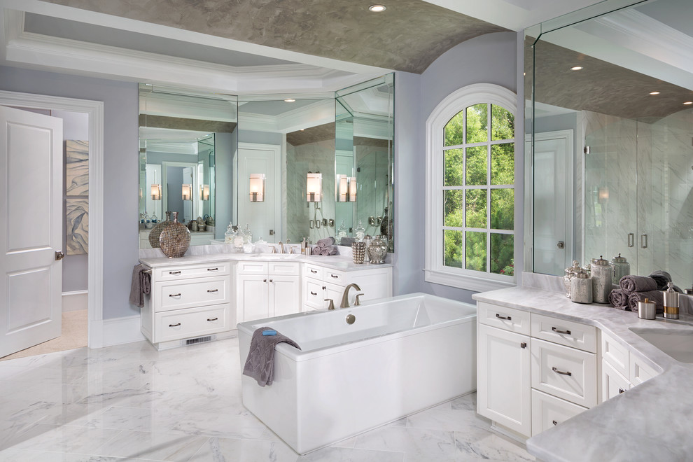 На фото: большая главная ванная комната в стиле неоклассика (современная классика) с фасадами в стиле шейкер, белыми фасадами, отдельно стоящей ванной, фиолетовыми стенами, мраморным полом, врезной раковиной и мраморной столешницей
