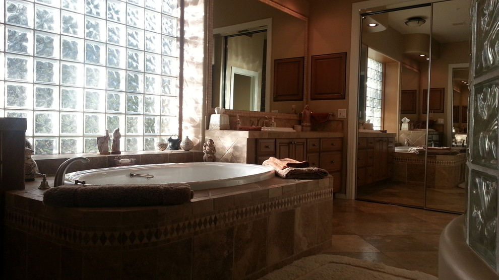 Immagine di una grande stanza da bagno padronale american style con lavabo da incasso, ante in legno chiaro, top piastrellato, vasca da incasso, doccia alcova, piastrelle beige, piastrelle in pietra, pareti beige e pavimento in travertino
