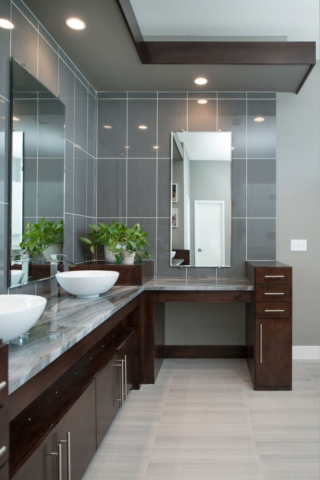 Design ideas for a large modern ensuite bathroom in Kansas City with flat-panel cabinets, dark wood cabinets, a freestanding bath, a corner shower, a two-piece toilet, blue tiles, grey tiles, glass tiles, grey walls, laminate floors, a vessel sink, granite worktops, beige floors and a hinged door.