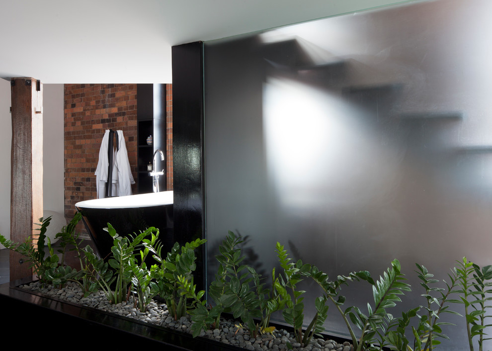 Exempel på ett mycket stort industriellt en-suite badrum, med släta luckor, svarta skåp, ett fristående badkar, svart kakel, svart och vit kakel, stickkakel, vita väggar, mörkt trägolv, ett fristående handfat, marmorbänkskiva och svart golv