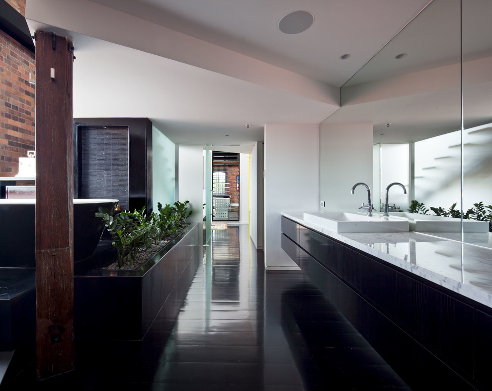 Свежая идея для дизайна: огромная главная ванная комната в стиле лофт с плоскими фасадами, черными фасадами, отдельно стоящей ванной, черной плиткой, черно-белой плиткой, удлиненной плиткой, белыми стенами, темным паркетным полом, настольной раковиной, мраморной столешницей и черным полом - отличное фото интерьера