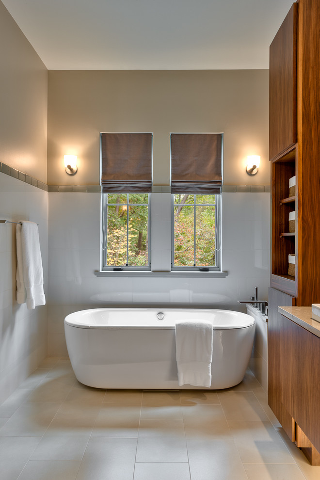Immagine di una stanza da bagno padronale contemporanea di medie dimensioni con ante lisce, ante in legno scuro, vasca freestanding, piastrelle bianche, pareti grigie e pavimento beige