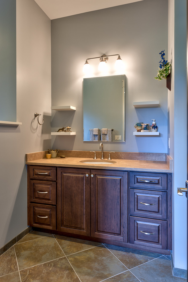 Cette photo montre une salle d'eau craftsman en bois foncé de taille moyenne avec un placard avec porte à panneau surélevé, un mur gris, un sol en carrelage de céramique, un lavabo encastré, un sol marron et un plan de toilette beige.