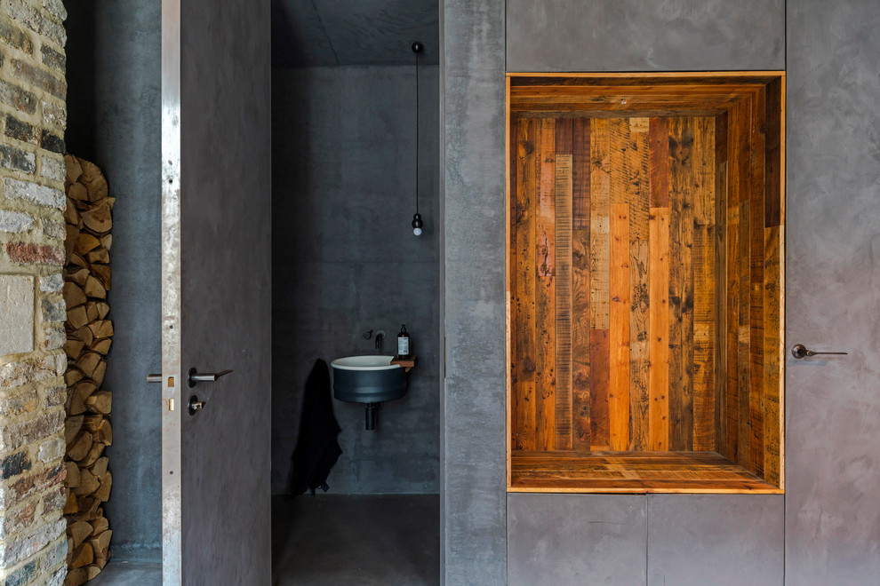 Immagine di una stanza da bagno industriale con piastrelle grigie, lavabo sospeso e pavimento grigio