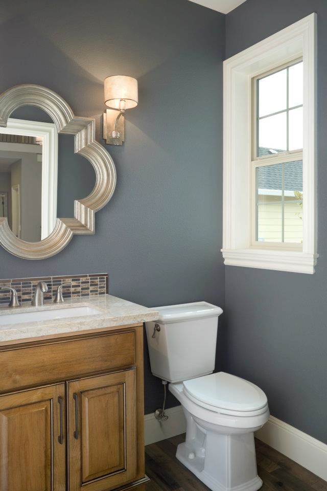 Immagine di una piccola stanza da bagno con doccia chic con ante con bugna sagomata, ante in legno chiaro, WC monopezzo, pareti grigie e lavabo sottopiano