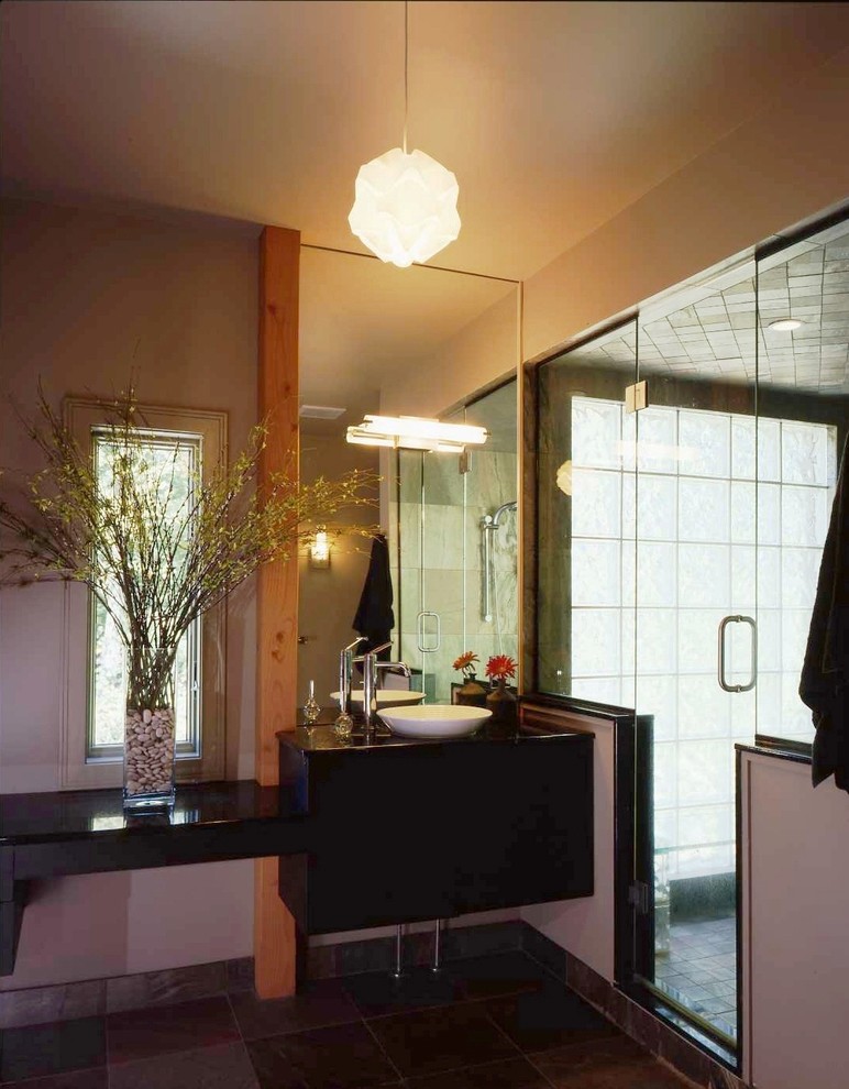 Exemple d'une grande salle de bain principale tendance avec un placard à porte plane, des portes de placard noires, un espace douche bain, un carrelage gris, des carreaux de céramique, un mur beige, un sol en carrelage de céramique, une vasque et un plan de toilette en granite.