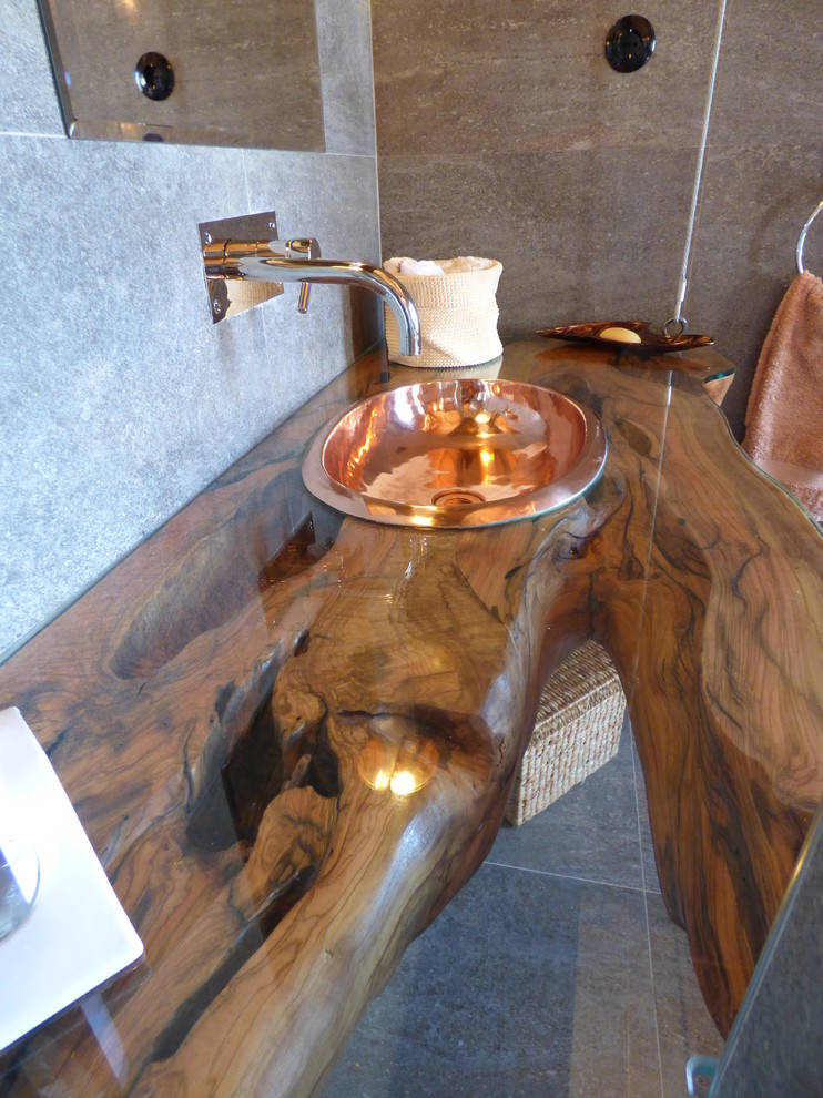 Bild på ett litet rustikt en-suite badrum, med ett nedsänkt handfat, träbänkskiva, ett fristående badkar, en toalettstol med hel cisternkåpa, grå kakel, keramikplattor, grå väggar och klinkergolv i keramik