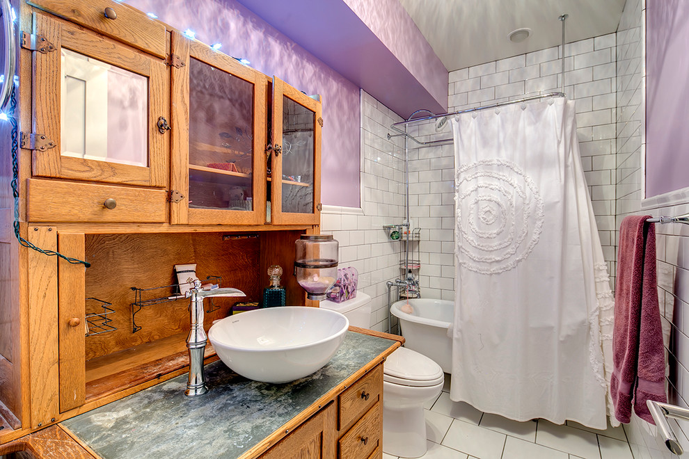 Bild på ett lantligt badrum, med ett fristående handfat, möbel-liknande, skåp i mellenmörkt trä, bänkskiva i zink, ett badkar med tassar, en dusch/badkar-kombination, en toalettstol med separat cisternkåpa, vit kakel, keramikplattor, lila väggar och klinkergolv i keramik