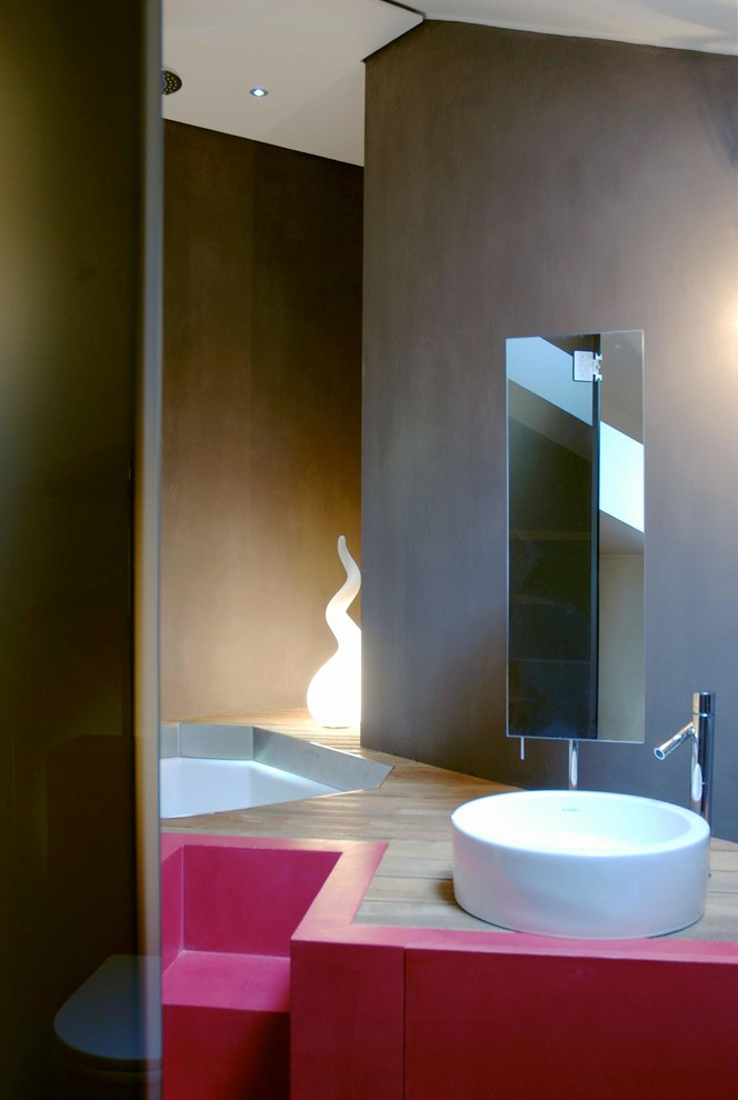 Bild på ett litet funkis en-suite badrum, med ett konsol handfat, luckor med infälld panel, skåp i mörkt trä, träbänkskiva, ett undermonterat badkar, en dusch i en alkov, brun kakel, glasskiva, bruna väggar och mörkt trägolv