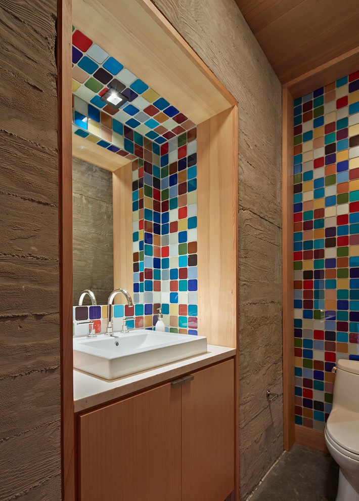 Diseño de cuarto de baño rural pequeño con lavabo sobreencimera, armarios con paneles lisos, puertas de armario de madera oscura, sanitario de una pieza y baldosas y/o azulejos multicolor