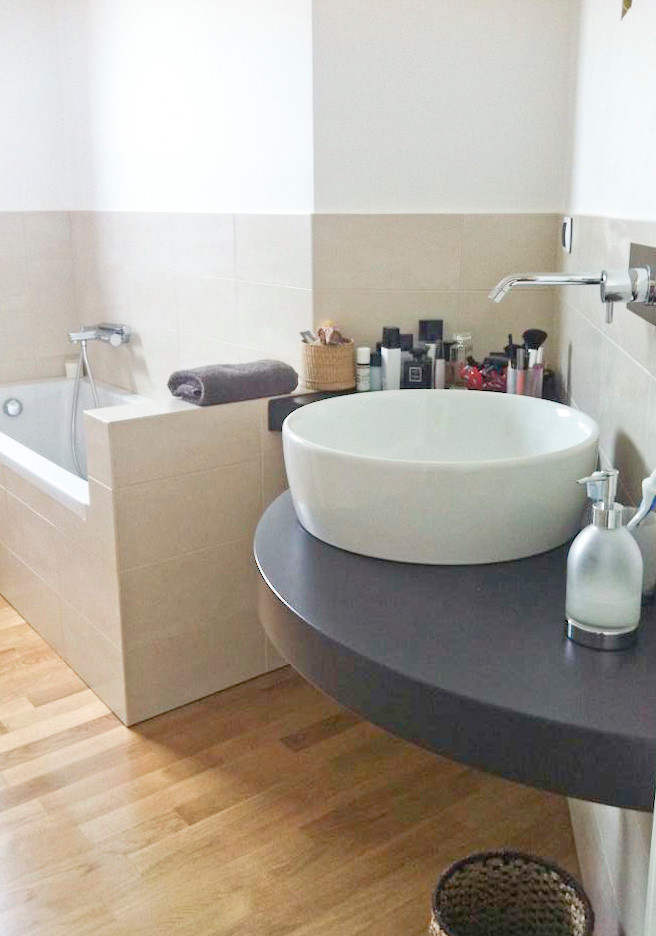 Ispirazione per una piccola stanza da bagno padronale minimalista con lavabo a consolle, top in legno, vasca ad angolo, bidè, piastrelle nere, piastrelle in ceramica, pareti beige e parquet chiaro
