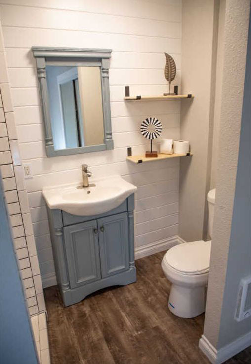 Design ideas for a small country bathroom in Portland with raised-panel cabinets, grey cabinets, an alcove shower, white tiles, ceramic tiles, grey walls, cement flooring, engineered stone worktops, black floors, a hinged door and white worktops.