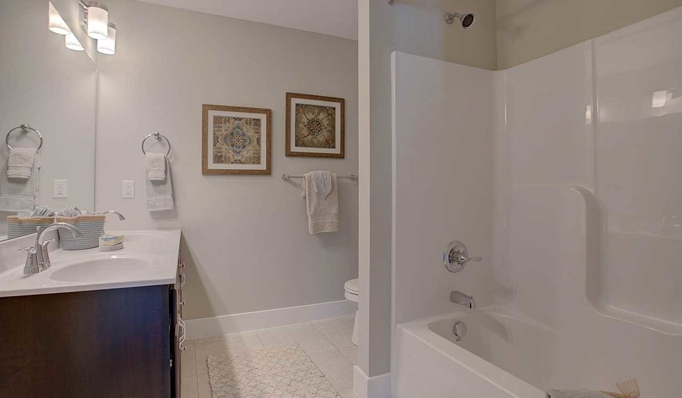 Großes Klassisches Duschbad mit dunklen Holzschränken, Duschbadewanne, Wandtoilette mit Spülkasten, grauer Wandfarbe, Keramikboden, integriertem Waschbecken, Marmor-Waschbecken/Waschtisch, weißem Boden und Duschvorhang-Duschabtrennung in Sonstige