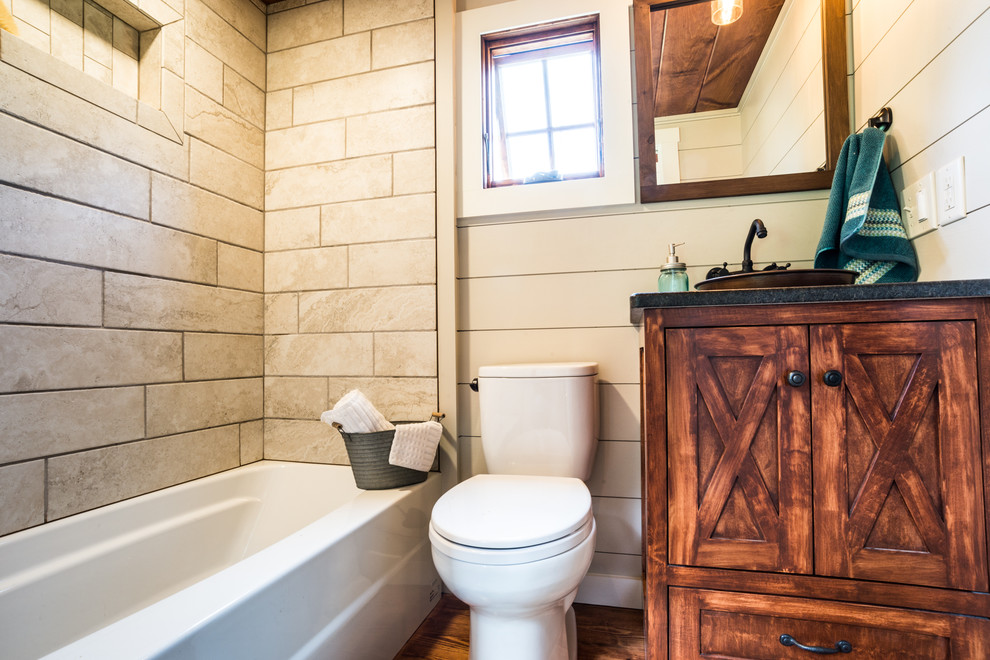 Immagine di una stanza da bagno american style con ante in stile shaker, ante in legno scuro, vasca da incasso, piastrelle in ceramica, pavimento in legno massello medio, lavabo a bacinella e top in granito