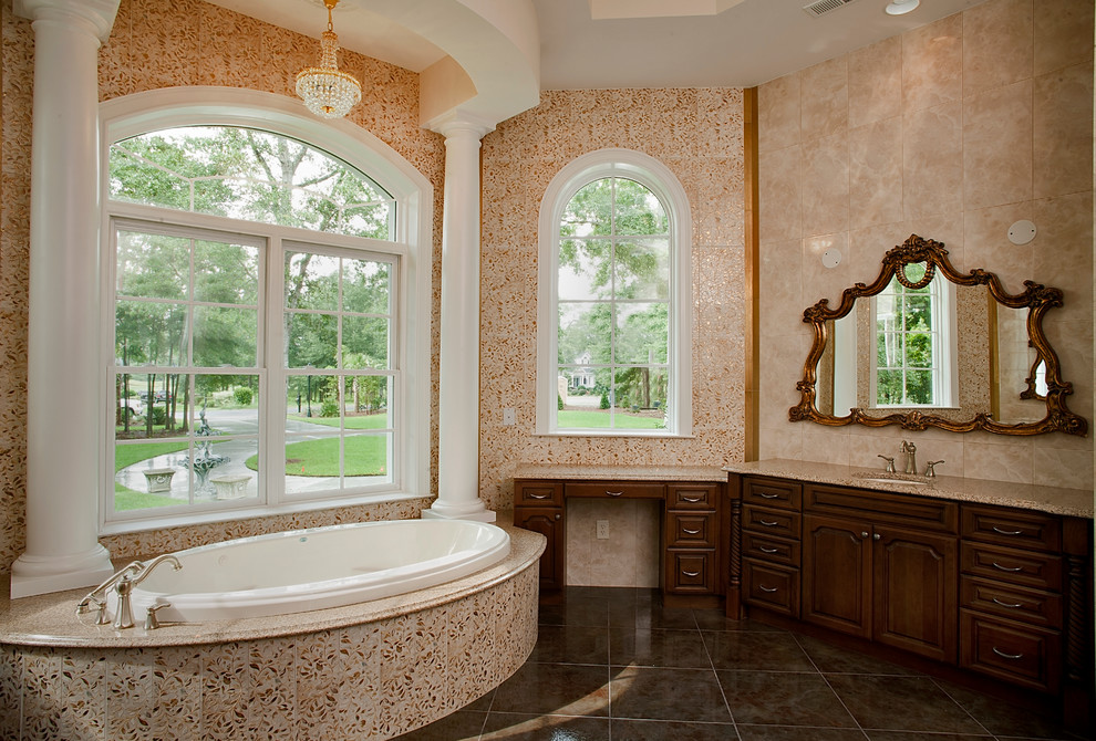 Inspiration for a large timeless master beige tile and ceramic tile travertine floor drop-in bathtub remodel in Charleston with raised-panel cabinets, dark wood cabinets, brown walls, an undermount sink and granite countertops