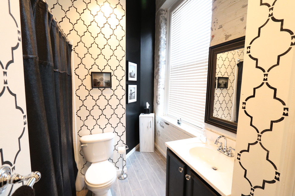 Bild på ett litet shabby chic-inspirerat en-suite badrum, med luckor med upphöjd panel, svarta skåp, ett platsbyggt badkar, en dusch/badkar-kombination, en toalettstol med hel cisternkåpa, vit kakel, porslinskakel, flerfärgade väggar, ljust trägolv, ett integrerad handfat och bänkskiva i akrylsten