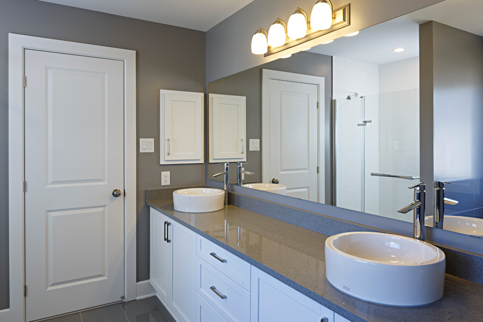 Пример оригинального дизайна: главная ванная комната в современном стиле с белыми фасадами, накладной ванной, угловым душем, серой плиткой, серыми стенами и настольной раковиной