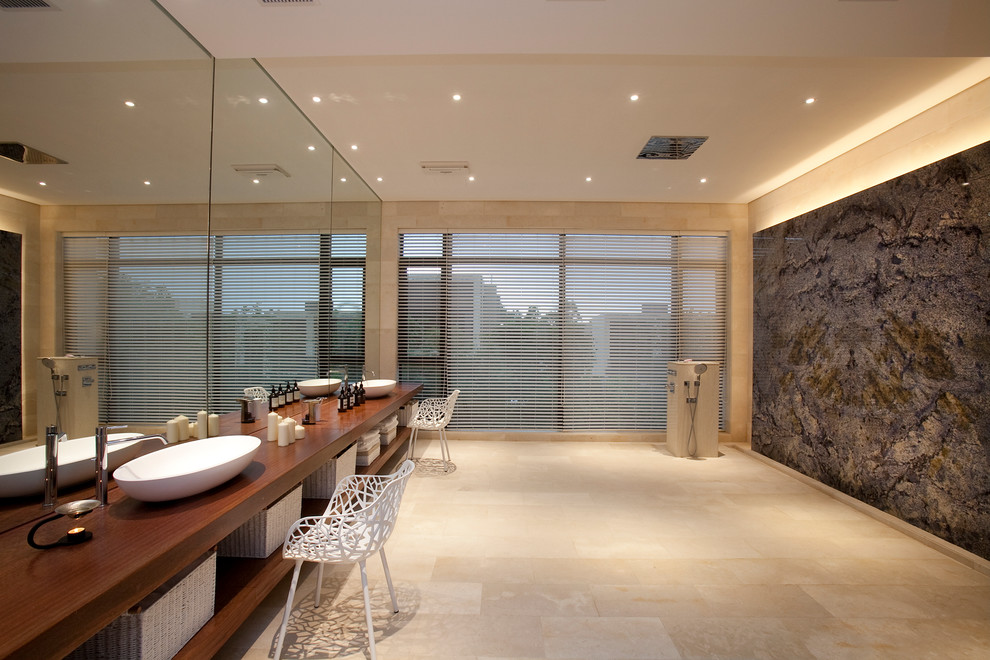 На фото: ванная комната в современном стиле с настольной раковиной, открытыми фасадами, фасадами цвета дерева среднего тона, столешницей из дерева, бежевой плиткой, бежевыми стенами и полом из травертина