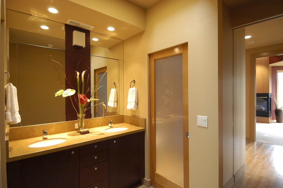 Modelo de cuarto de baño contemporáneo con lavabo bajoencimera, armarios con paneles lisos y puertas de armario de madera en tonos medios
