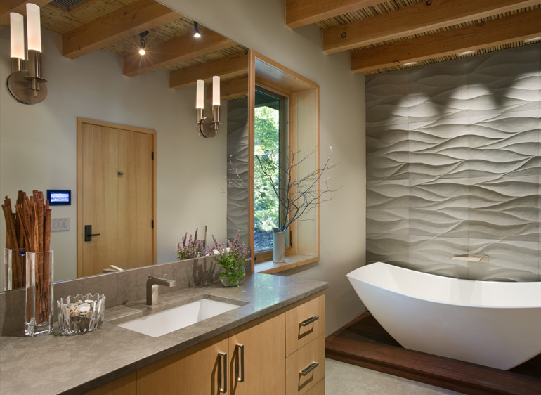 Bild på ett funkis en-suite badrum, med ett undermonterad handfat, släta luckor, skåp i mellenmörkt trä, bänkskiva i kvarts, ett fristående badkar, grå kakel, keramikplattor, vita väggar och klinkergolv i keramik