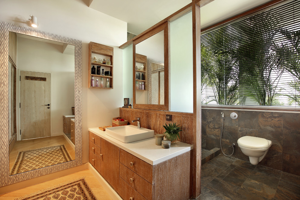 Badezimmer En Suite mit flächenbündigen Schrankfronten, hellen Holzschränken, offener Dusche, braunen Fliesen, weißer Wandfarbe, hellem Holzboden, Aufsatzwaschbecken und offener Dusche in Ahmedabad