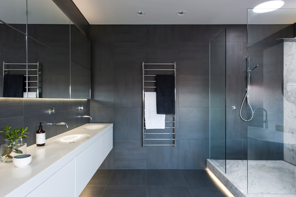 Idéer för ett stort modernt en-suite badrum, med ett integrerad handfat, vita skåp, bänkskiva i akrylsten, ett fristående badkar, en öppen dusch, grå kakel, keramikplattor, grå väggar, klinkergolv i keramik, släta luckor och med dusch som är öppen