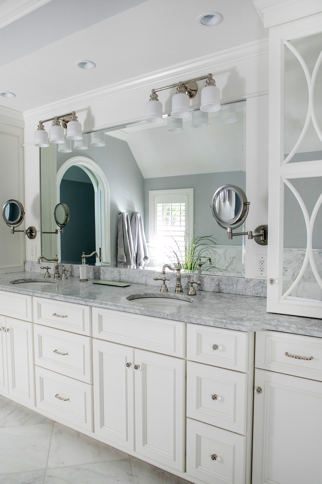 Large transitional master white tile and marble tile marble floor and white floor bathroom photo in Milwaukee with furniture-like cabinets, white cabinets, a two-piece toilet, white walls, an undermount sink, marble countertops, a hinged shower door and white countertops